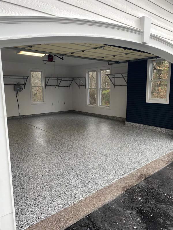 Spacious garage interior featuring light gray speckled epoxy flooring