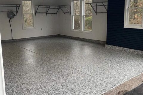 Spacious garage interior featuring light gray speckled epoxy flooring