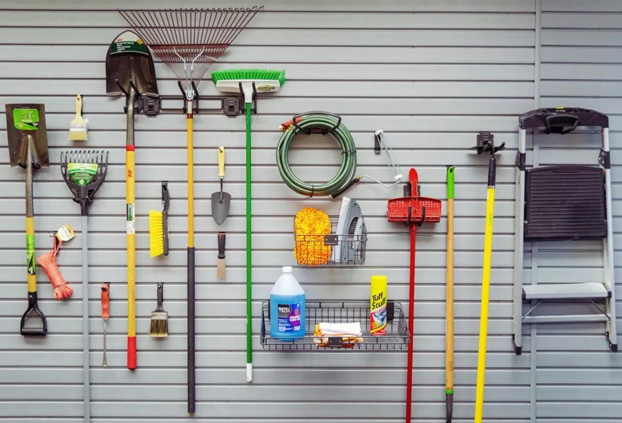 A variety of garden tools are neatly organized on a wall-mounted rack