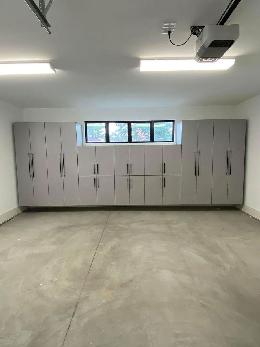 Wall of sleek, gray storage cabinets with handles, under a small strip of windows