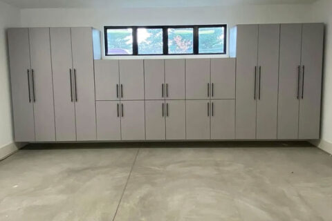 Wall of sleek, gray storage cabinets with handles, under a small strip of windows